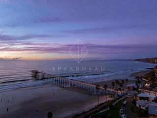 Overhead drone photo of Scripps Pier during sunset in La Jolla Shores San Diego California highlighting ocean texture and glowing horizon