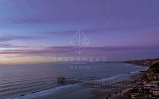 Overhead drone photo of Scripps Pier during sunset in La Jolla Shores San Diego California highlighting ocean texture and glowing horizon