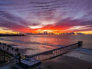 Overhead drone photo of Scripps Pier during sunset in La Jolla Shores San Diego California highlighting ocean texture and glowing horizon