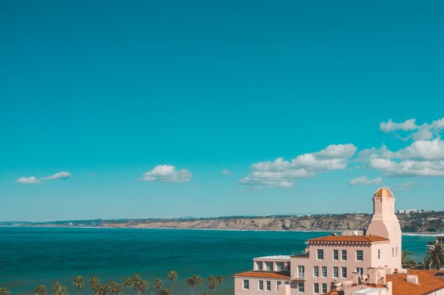Elevated view of the cliffs, palm trees and the ocean at La Jolla Cove.