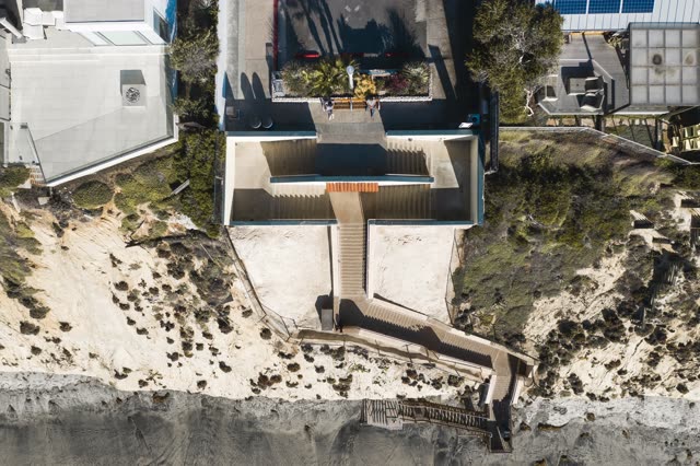 Aerial view of the cliffs, the buildings and the beach in Encinitas, with people walking.