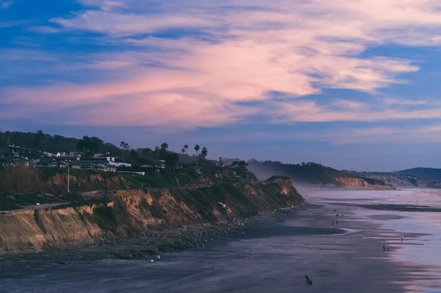 Elevated view of the cliffs, wildlife and the ocean in Del Mar, with people walking.