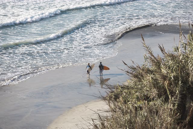 Elevated view of the beach, the surf and the ocean in Encinitas, with people walking.