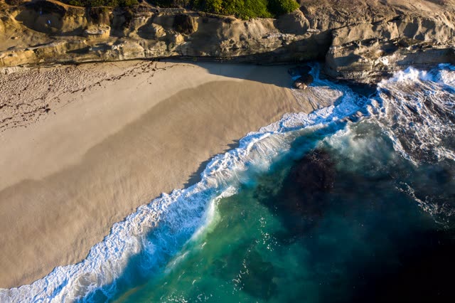 Aerial view of the cliffs, the surf and the ocean at La Jolla Cove.