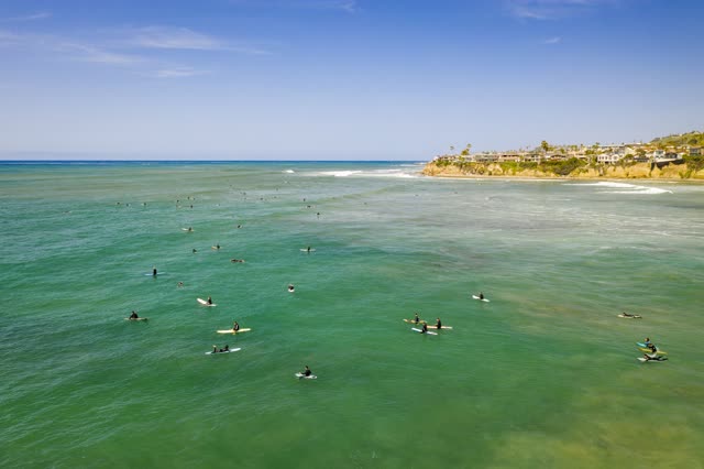 Aerial view of the beach, the surf and the ocean in Pacific Beach, with surfers out.