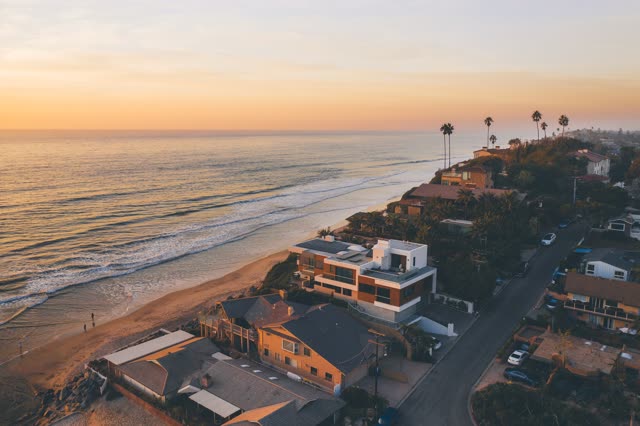 Aerial view of the beach, palm trees and the ocean at Moonlight Beach, with people walking.