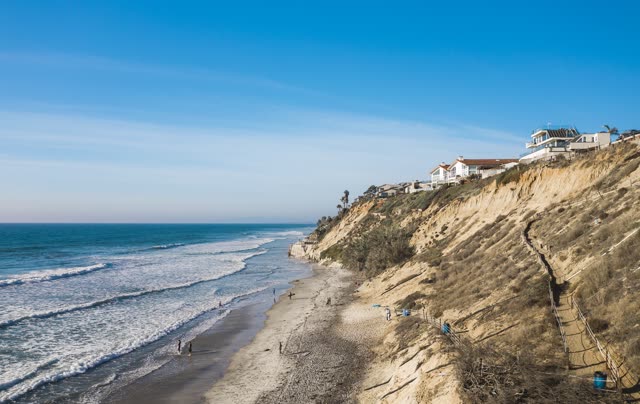 Aerial view of the cliffs, the surf and the ocean in Encinitas, with people walking.