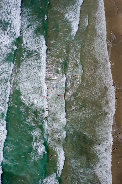 Aerial view of the beach, the surf and the ocean at Leucadia, with swimmers in the water.