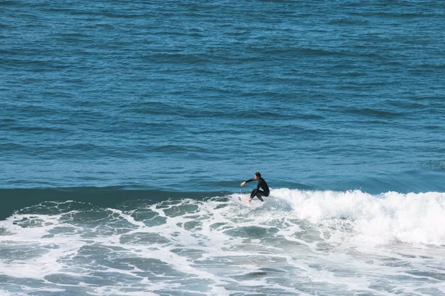 Low aerial view of the beach, the surf and the ocean in Encinitas, with surfers out.
