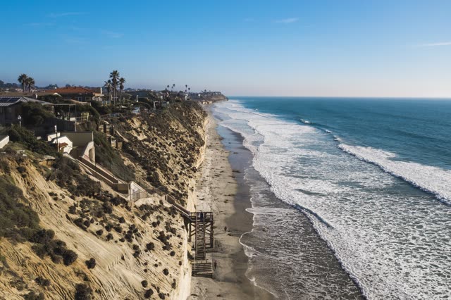 Aerial view of the cliffs, the surf and palm trees in Encinitas.