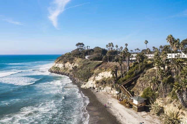 Aerial view of the beach, the surf and palm trees at Swamis, with people walking.