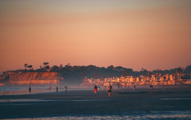 The beach, the ocean and homes in Del Mar, with people walking.