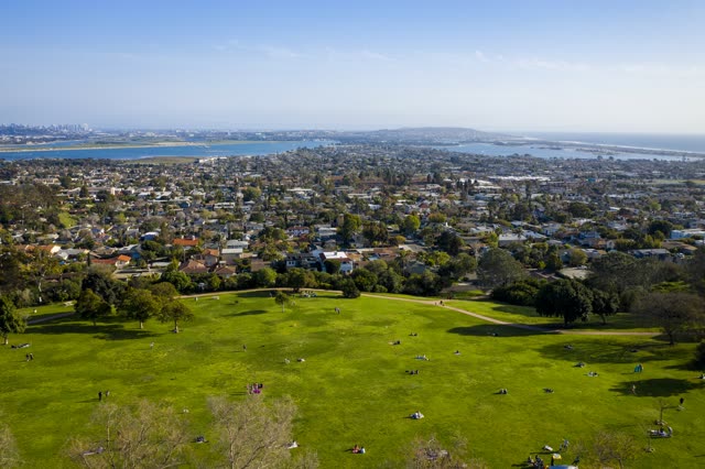 Aerial view of a park, the skyline and the bay in Pacific Beach, with a crowd gathered.