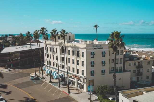 Low aerial view of the downtown streets, the surf and palm trees at La Jolla Cove.