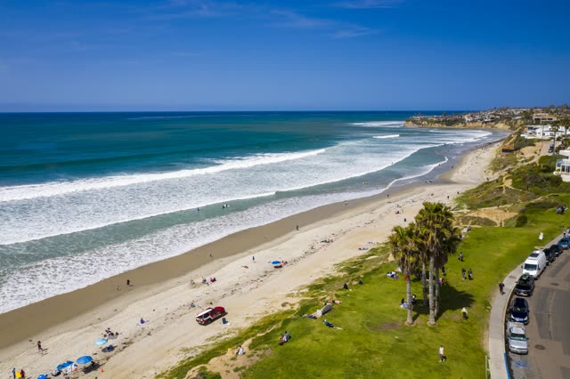 Aerial view of the beach, the surf and palm trees in Pacific Beach, with people walking.