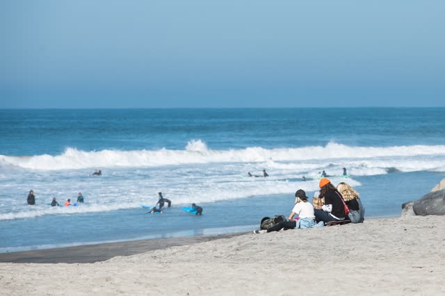 The beach, the surf and the ocean at Moonlight Beach, with surfers out.