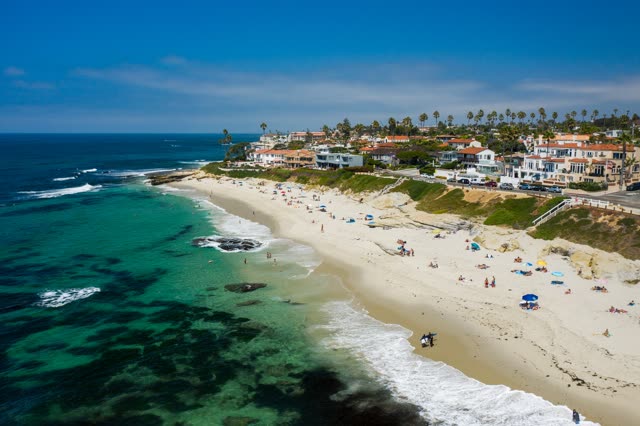 Aerial view of the beach, the surf and palm trees at Windansea, with people walking.
