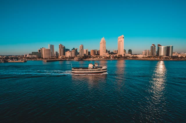 Helicopter shot of a ferry boat in the San Diego Bay with the skyline in the background | Aerial Photo
