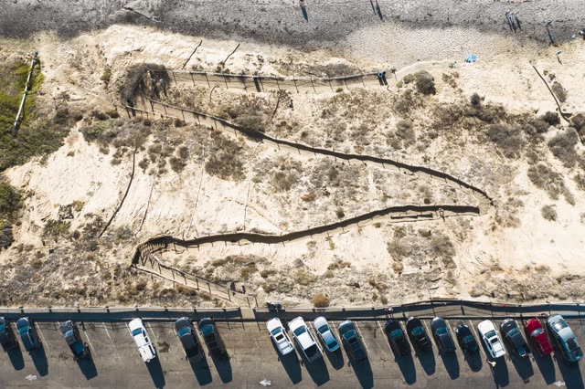 Aerial view of the beach, traffic and open country in Encinitas, with people walking.