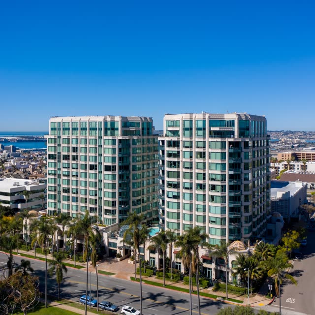 Low aerial view of a residential street, palm trees and the bay at Bankers Hill.