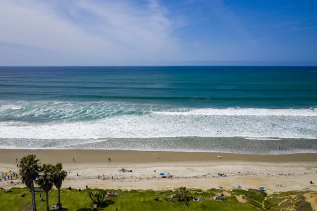 Aerial view of the beach, the surf and palm trees in Pacific Beach, with people walking.