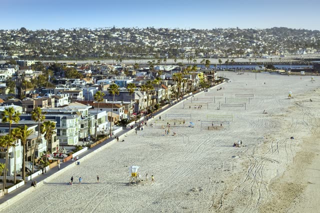 Aerial view of the beach, palm trees and the ocean in Mission Bay, with people walking.