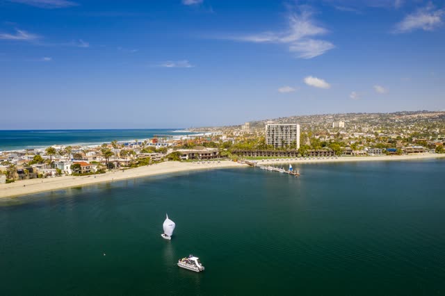 Aerial view of the beach, boats and palm trees in Mission Bay, with boats out.