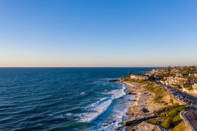 Aerial view of the cliffs, the surf and the ocean at Windansea, with people walking.