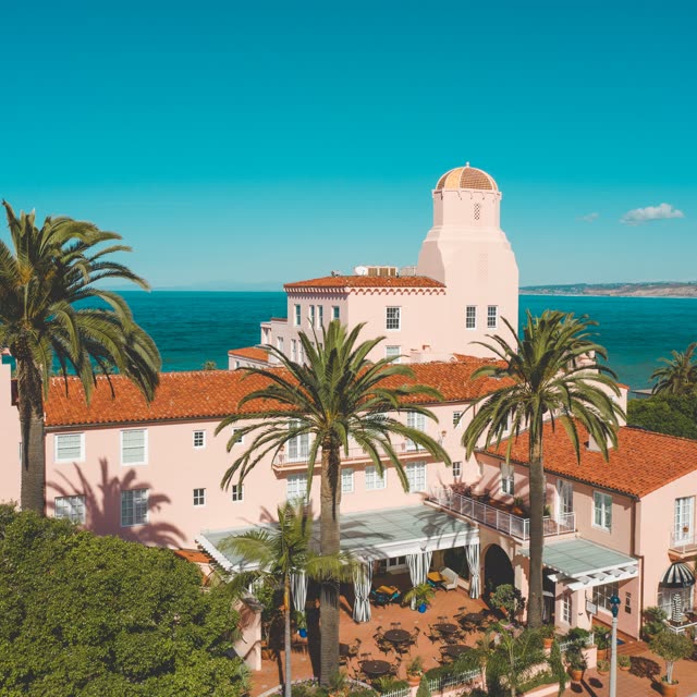 Low aerial view of the beach, palm trees and the ocean at La Jolla Cove.