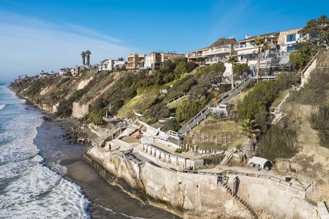 Aerial view of the cliffs, the surf and palm trees in Encinitas.