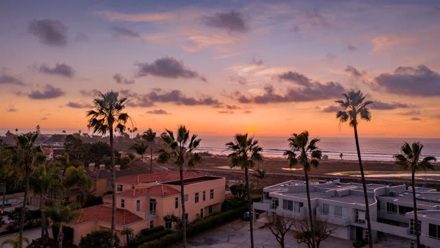 Low aerial view of a residential street, palm trees and the ocean in Solana Beach.