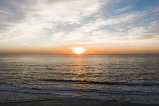 Low aerial view of the beach, the surf and the ocean at Moonlight Beach.