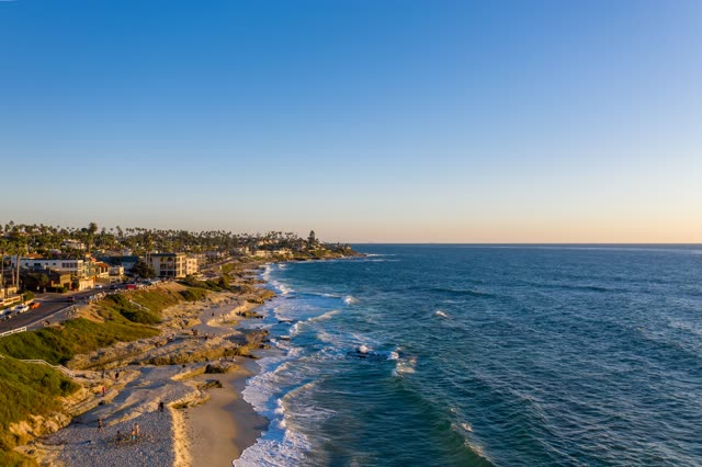 Aerial view of the beach, the surf and palm trees at Windansea, with people walking.