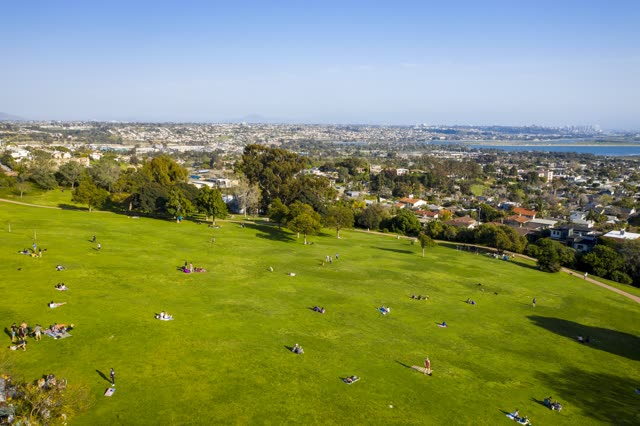 Aerial view of a park, the skyline and the bay in Pacific Beach, with a crowd gathered.