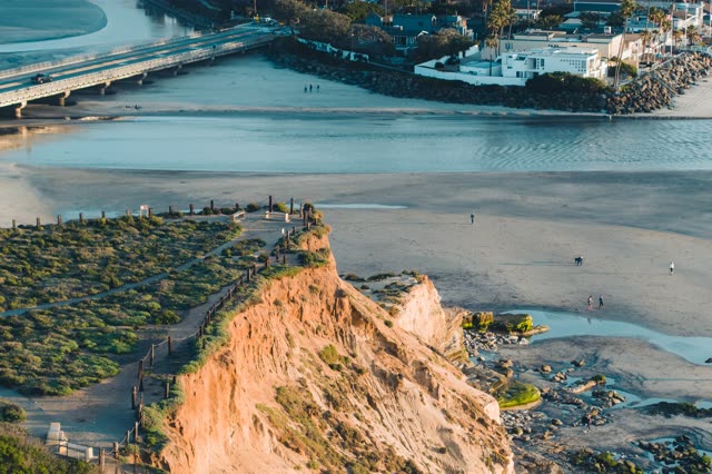 Aerial view of the cliffs, the bridge and palm trees in Del Mar, with people walking.