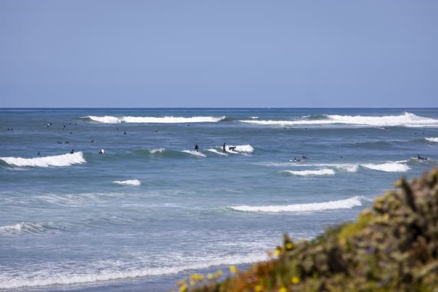 Elevated view of the beach, the surf and the ocean in Pacific Beach, with surfers out.