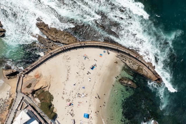 Aerial view of the beach, the surf and the ocean at La Jolla Cove, with people walking.