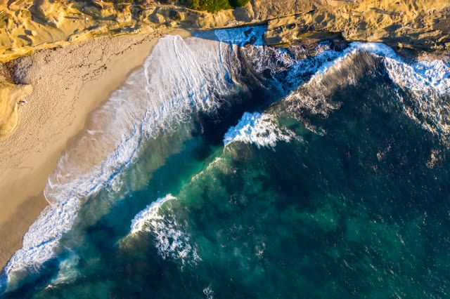Aerial view of the cliffs, the surf and the ocean at La Jolla Cove.