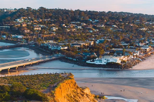 Elevated view of the cliffs, the bridge and palm trees in Del Mar, with people walking.