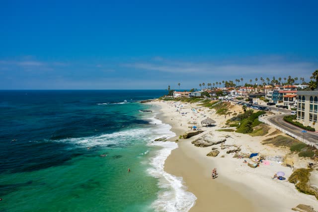 Aerial view of the beach, the surf and palm trees at Windansea, with people walking.