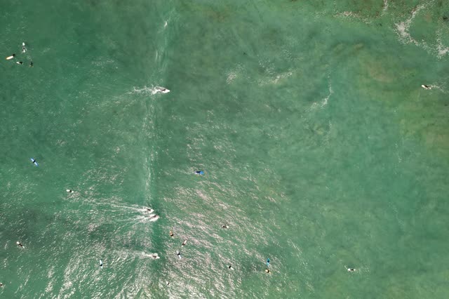 Aerial view of the beach, the surf and the ocean in Pacific Beach, with surfers out.