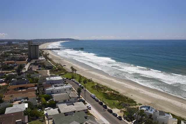 Aerial view of the beach, the surf and the pier in Pacific Beach, with people walking.
