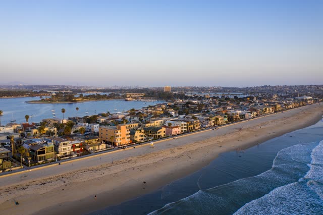 Aerial view of the beach, the skyline and boats in Mission Bay, with people walking.