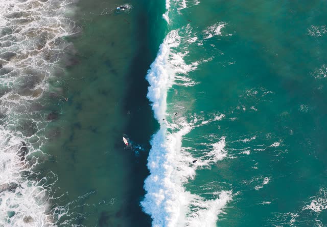 Aerial view of the beach, the surf and the ocean in Encinitas, with surfers out.