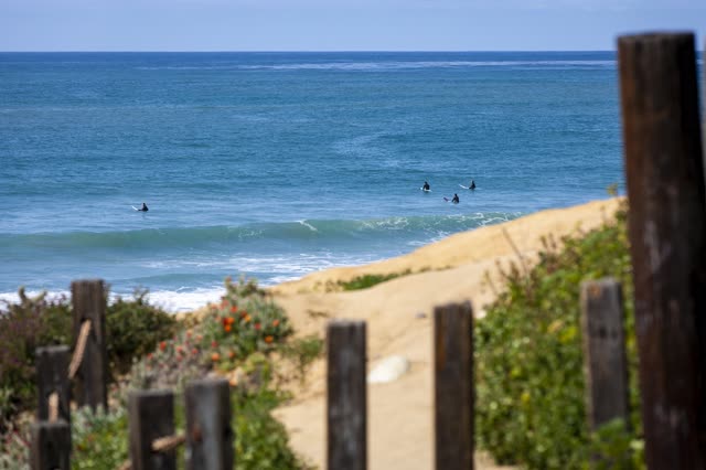Elevated view of the beach, the surf and the ocean in Pacific Beach, with surfers out.