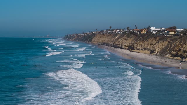 Aerial view of the beach, the surf and palm trees in Encinitas, with surfers out.