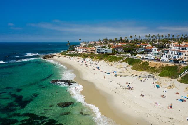 Aerial view of the beach, the surf and palm trees at Windansea, with people walking.