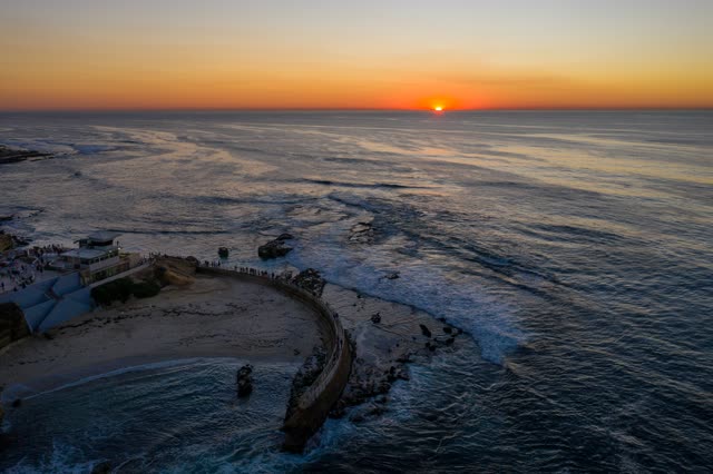 Aerial view of the beach, the surf and the ocean at La Jolla Cove, with a crowd gathered.