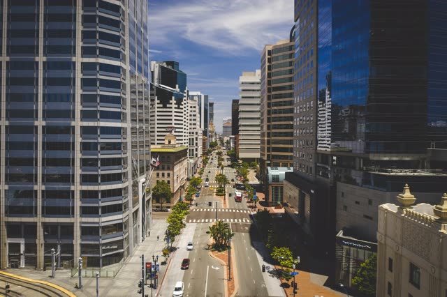 Low aerial view of the downtown streets, the skyline and palm trees at Waterfront, with people walking.