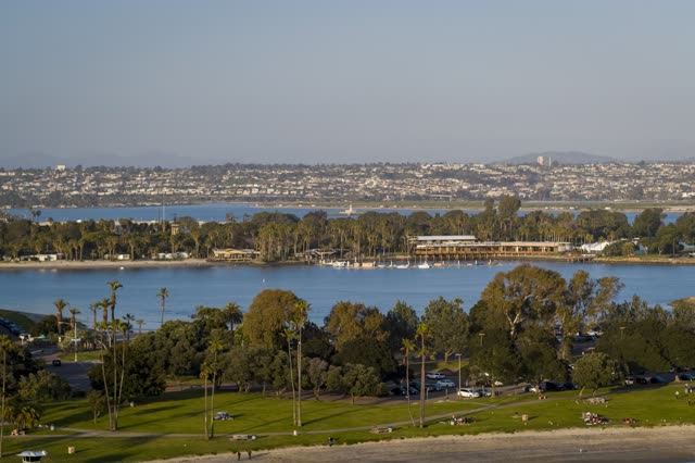 Aerial view of a park, boats and palm trees in Mission Bay, with a crowd gathered.